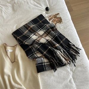 Flat lay of soft black, white, and brown plaid scarf with fringe and beige knit vest