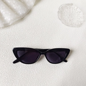 Chic black cat-eye sunglasses on a white textured background with lace and glass plate