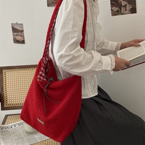 Close-up of red boucle shoulder bag featuring checked lining and drawstring detail