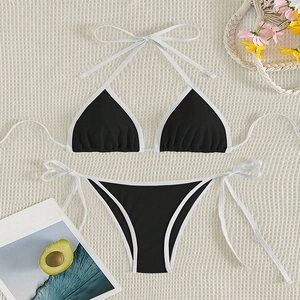 Flat lay of black and white color block bikini set on a textured beige woven mat