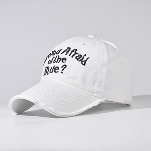 Detail of white cotton baseball cap with black embroidery and distressed frayed brim edges