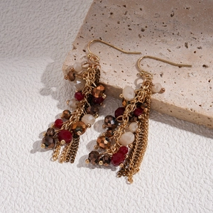 Close-up of bohemian star chain earrings with red and brown glass beads on stone