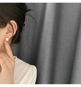 Detail view of gold-trimmed rectangular white shell earrings on a model's ear