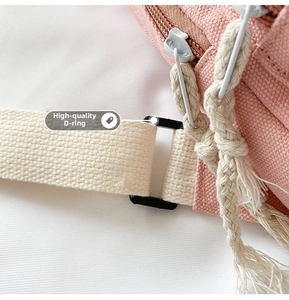 Detail view of pink canvas chest bag featuring a durable D-ring buckle and double zippers
