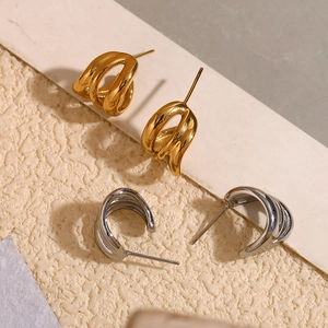 Macro view of gold and silver layered wavy stud earrings on a textured background