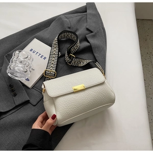 Détail de la texture cuir litchi blanc et fermoir doré avec bandoulière géométrique