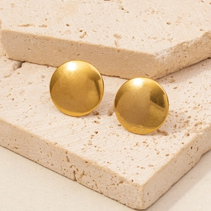 Macro shot of minimalist gold round stud earrings displayed on elegant stone bases