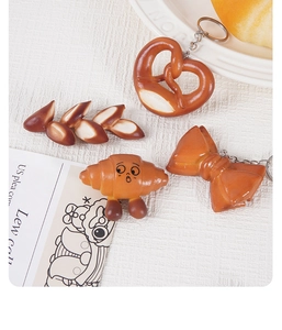 Λεπτομέρεια από μπρελόκ ψωμιού PVC με σχήματα pretzel και κρουασάν σε λευκό πιάτο