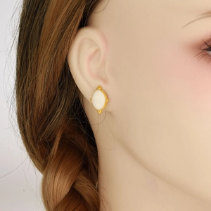Detail of vintage oval stud earrings in 18K gold plating with white shell inlay on model