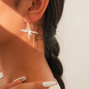 Artistic lighting on a silver iris flower earring worn by a model in a close-up shot