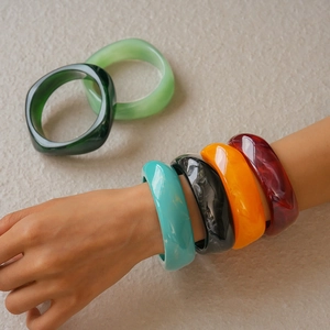 Close-up of wave-shaped thick resin bangles with elegant marble patterns in various colors