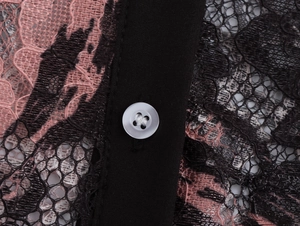 Macro shot of delicate pink lace fabric with a white button and black placket detail