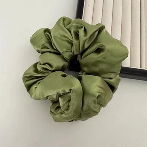 Detail of grass green satin oversized scrunchie with silky pleated texture and soft shine