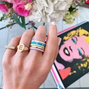 Gold-plated rings set featuring colorful enamel bands and letter E signet ring on model
