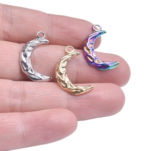 Detailed view of three hammered stainless steel crescent moon charms in gold, silver, and purple