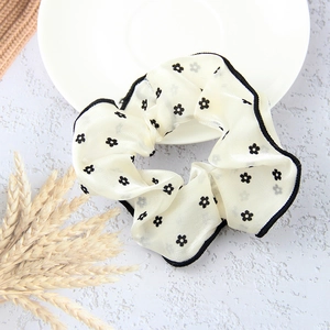 Summer Korean white mesh scrunchie with black flower pattern on a decorative ceramic plate