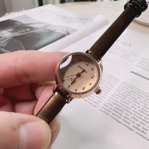 Elegant women's quartz watch with rose gold case and brown leather strap held by hand
