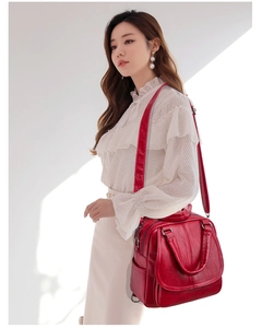 Detalle de mochila de cuero sintético rojo con cremalleras plateadas y herrajes de moda