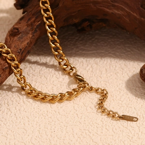 Detail of 18K gold-plated curb chain with lobster clasp and engraved logo tag