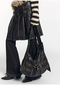 Detail of vintage black tote bag featuring decorative straps and rustic metal hardware