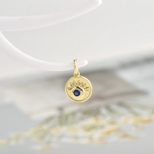 Golden evil eye pendant with blue zircon center and radiant sunburst metal pattern