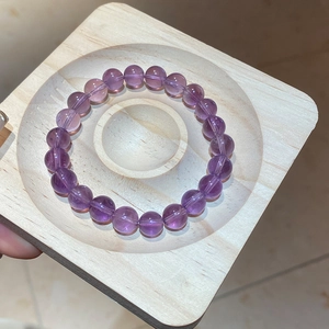 Macro shot of natural purple amethyst beaded bracelet on a light wooden display tray