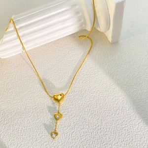 Detailed view of gold stainless steel necklace with three heart pendants and zircons