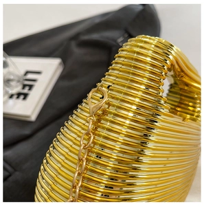 Detail of gold metal evening bag with horizontal spiral texture and light gold chain