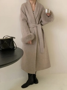 Détail d'un manteau en laine beige avec poignets en fourrure et ceinture à la taille