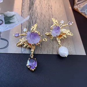 Asymmetric gold butterfly earrings with purple crystals and freshwater pearl tassels