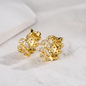 18K gold plated hoop earrings with zircon leaf design on white textured background