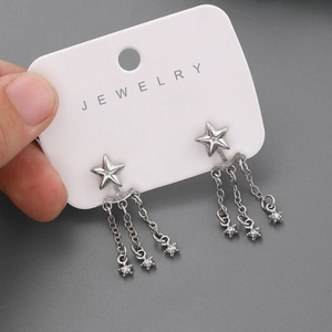Détail des boucles d'oreilles étoile en argent avec de longues chaînes à pompons fins