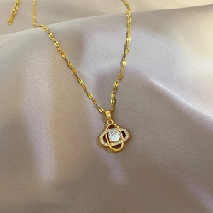 Macro shot of gold clover-style pendant with sparkling stones on lavender silk