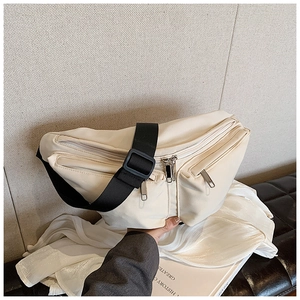 Detail of beige crossbody chest bag with adjustable black wide strap and silver zippers