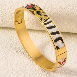 Detail view of gold enamel bangle with colorful abstract patterns and hinged clasp