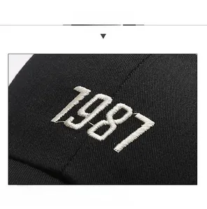 Close-up of white 1987 embroidery on black cotton twill baseball cap fabric