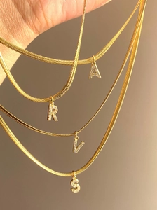 Detail of gold snake chains with crystal-encrusted alphabet pendants A, R, V, S