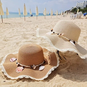 Detail of straw hat with shell beads, white lace trim and intricate weaving texture