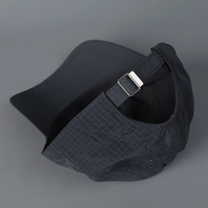 Close-up of dark grey ripstop grid fabric on baseball cap with silver metal adjustment buckle