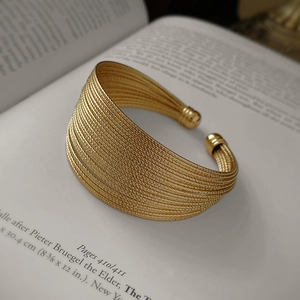 Detailed macro shot of multilayer gold-plated wide cuff bracelet with spiral textures