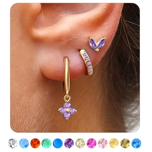 Detail of gold cartilage hoop earrings set with purple floral and gemstone accents