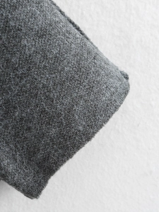 Vista macro dettagliata della trama in maglia grigia e fibre di lana del cardigan poncho