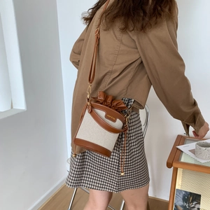 Retro canvas and brown leather bucket bag with drawstring closure shown on shoulder