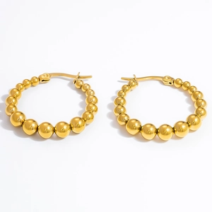 Close-up of golden beaded hoop earrings with a gradient polished finish on white background
