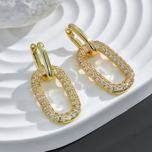 Detailed shot of gold earrings featuring white zircon pavé on white stone tray