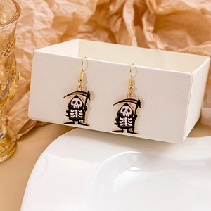 Close-up of Grim Reaper drop earrings with skull details and gold ear hooks