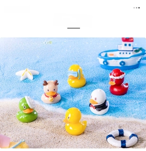 Miniature resin yellow ducks with diverse themed hats on decorative white sand beach