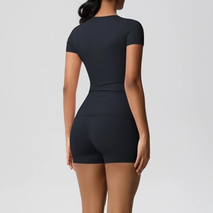 Rear view of model wearing black tight elastic yoga set with short sleeves and shorts