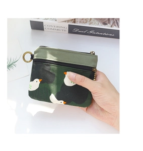 Gros plan d'un petit sac en toile verte à deux fermetures éclair avec motif canard
