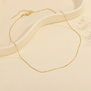 Detail of adjustable 18K gold plated chain necklace with lobster clasp and slider bead